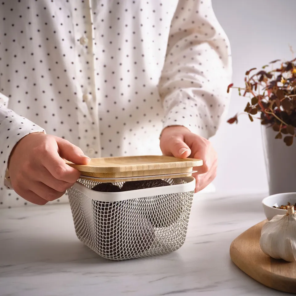 Person holding an IKEA 365+ mesh food basket with lid, showing air circulation for food storage.