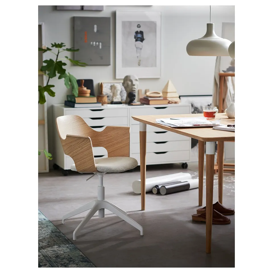 Modern office setup with light wood chair, white base, adjustable height, and sleek desk.