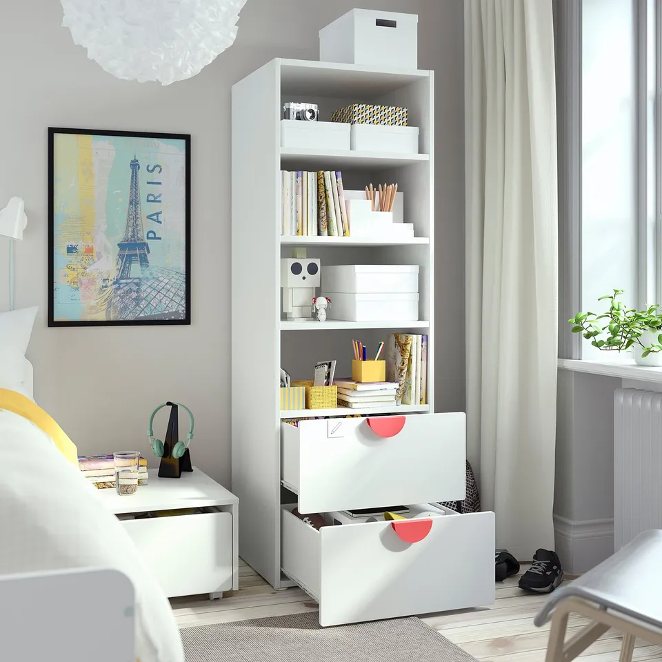 Bright bedroom with SMÅSTAD bookcase, storing books, toys, and crafts. Anchored to the wall for safety.