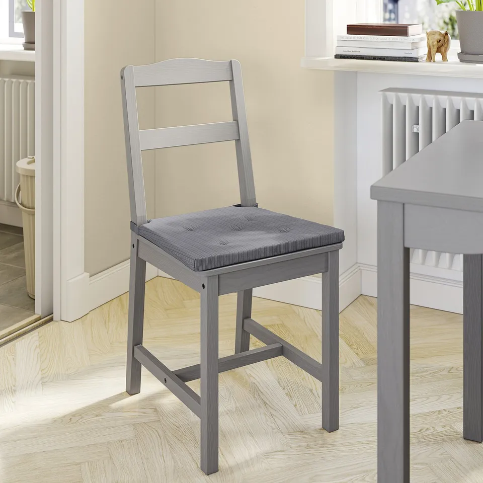 A grey wooden chair with a cushioned seat in a modern room.