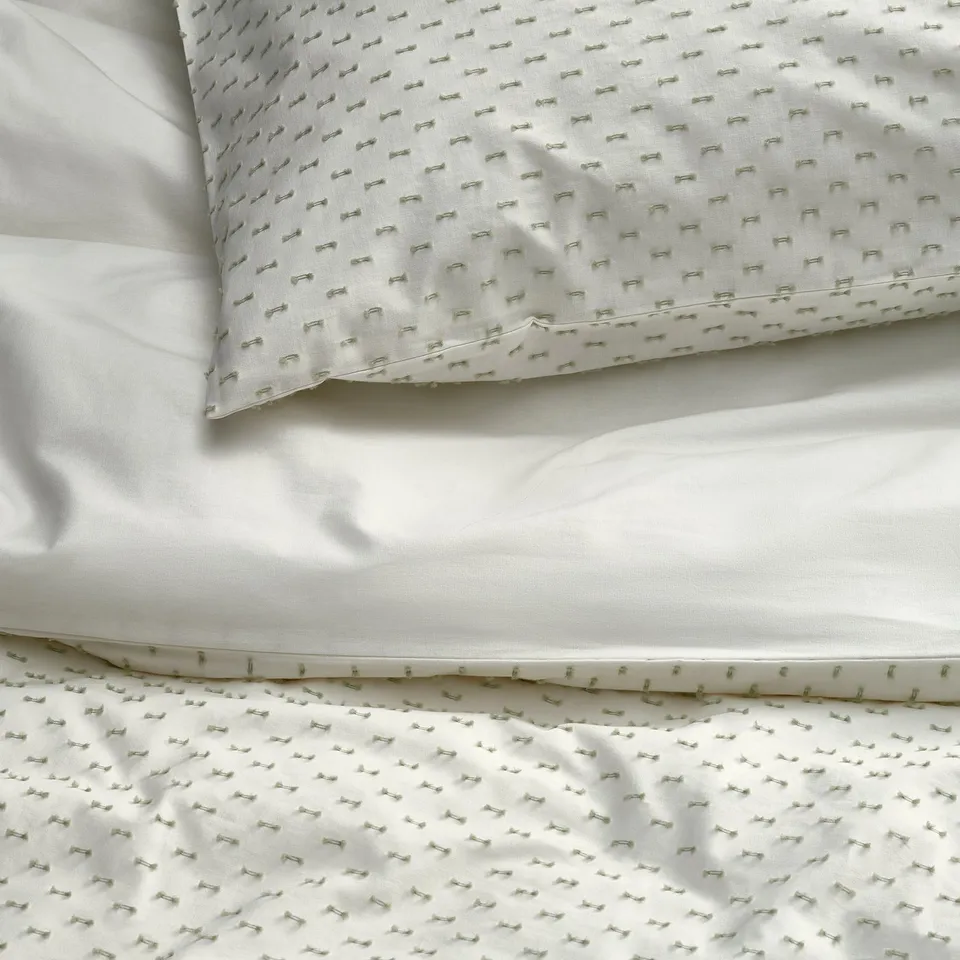 Crisp, white bedding with elegant, green woven texture, showcasing high-quality cotton craftsmanship.