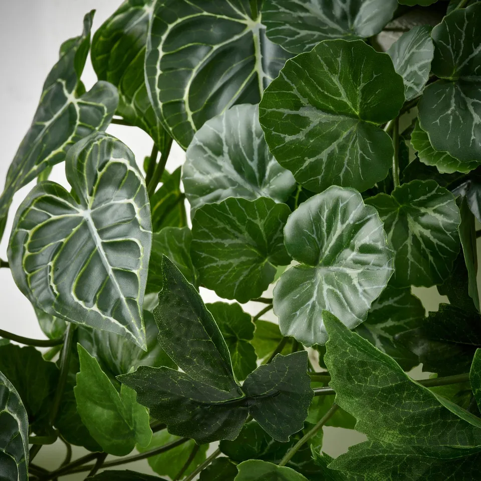 Lush, realistic artificial greenery, with varied green hues and intricate leaf veins, showcasing lifelike quality and intricate detailing.