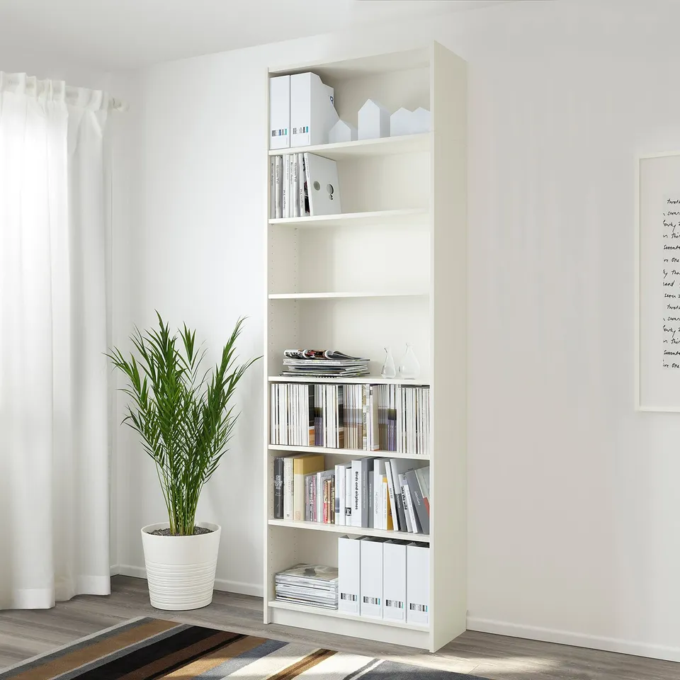 White BILLY bookcase, a tall, slim storage unit. Holds books, files, and decor items. Tall, fits into small spaces efficiently.