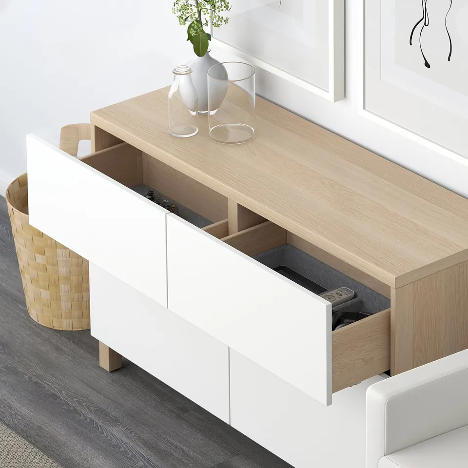 Modern sideboard with open drawers and shelves. Remote and electronic devices stored in visible drawer. Minimalist decor with vases on top.