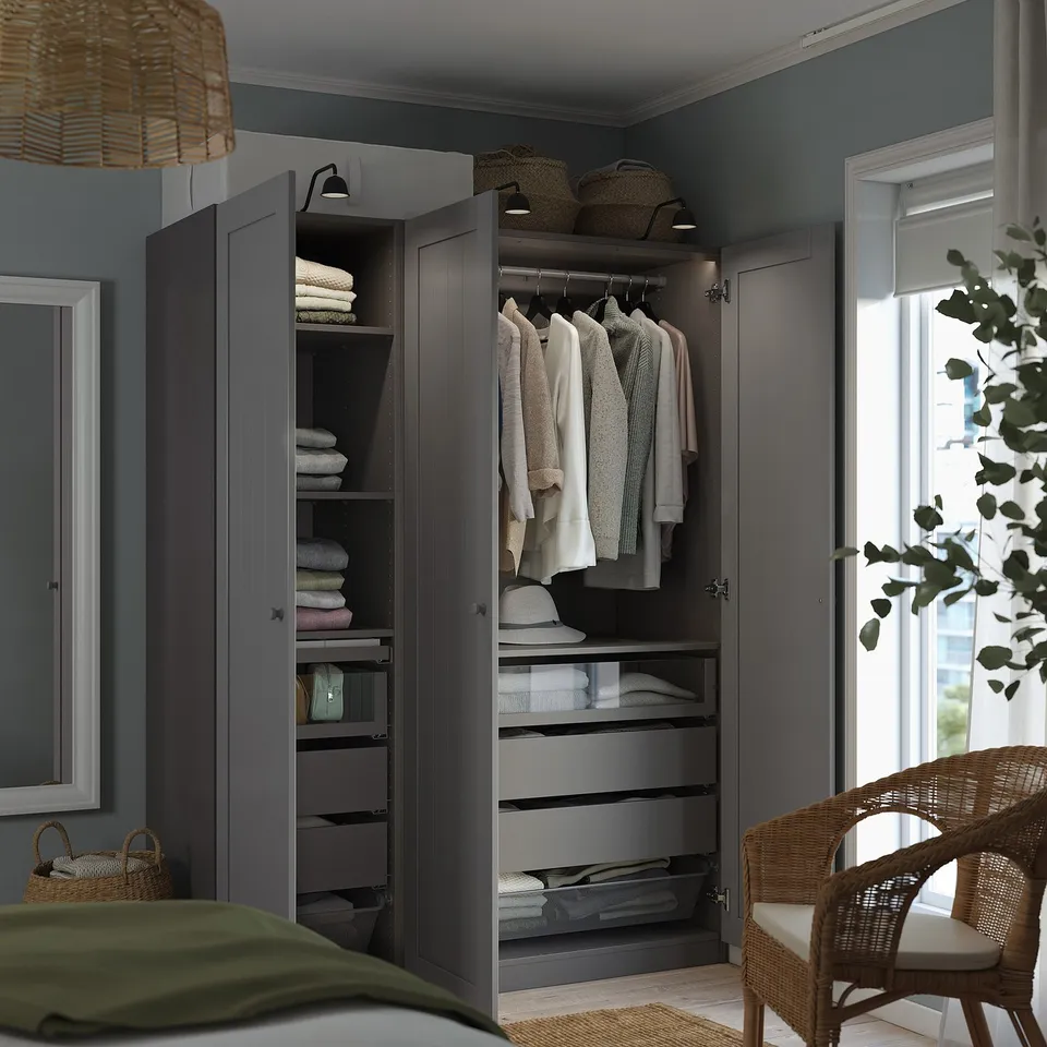 A modern bedroom with an open PAX wardrobe, showcasing storage options like shelves, drawers, and hanging space for clothes.