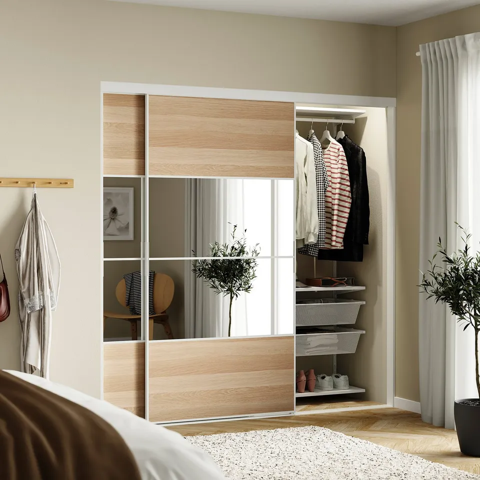 Bedroom with SKYTTA mirrored sliding closet, striped shirt, jacket, plant, thin curtains, beige walls.