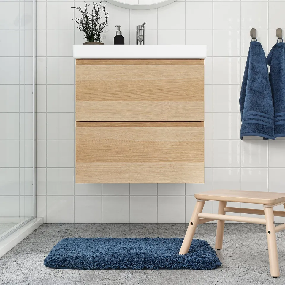 Modern bathroom with wooden vanity, mirror, blue towels, and ALMTJÄRN mat.