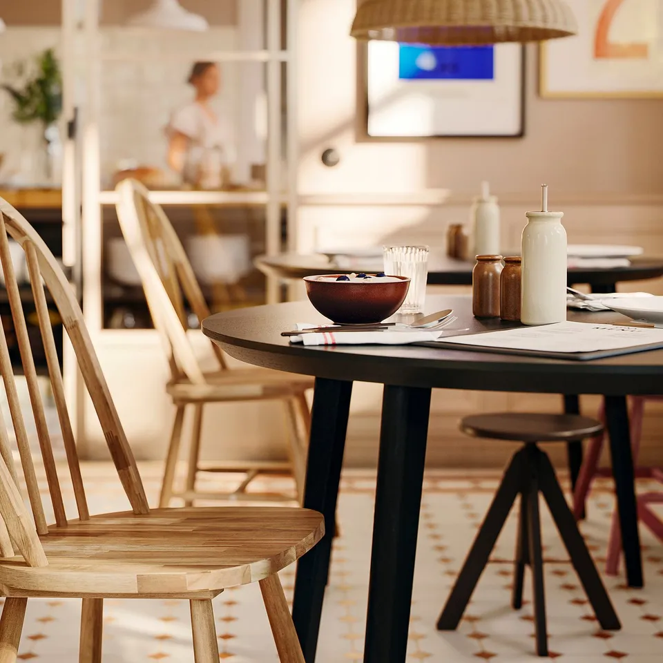 Wooden café with stoneware, blurred person, minimalist. Or minimalist café with wooden chairs, table and blurred person.