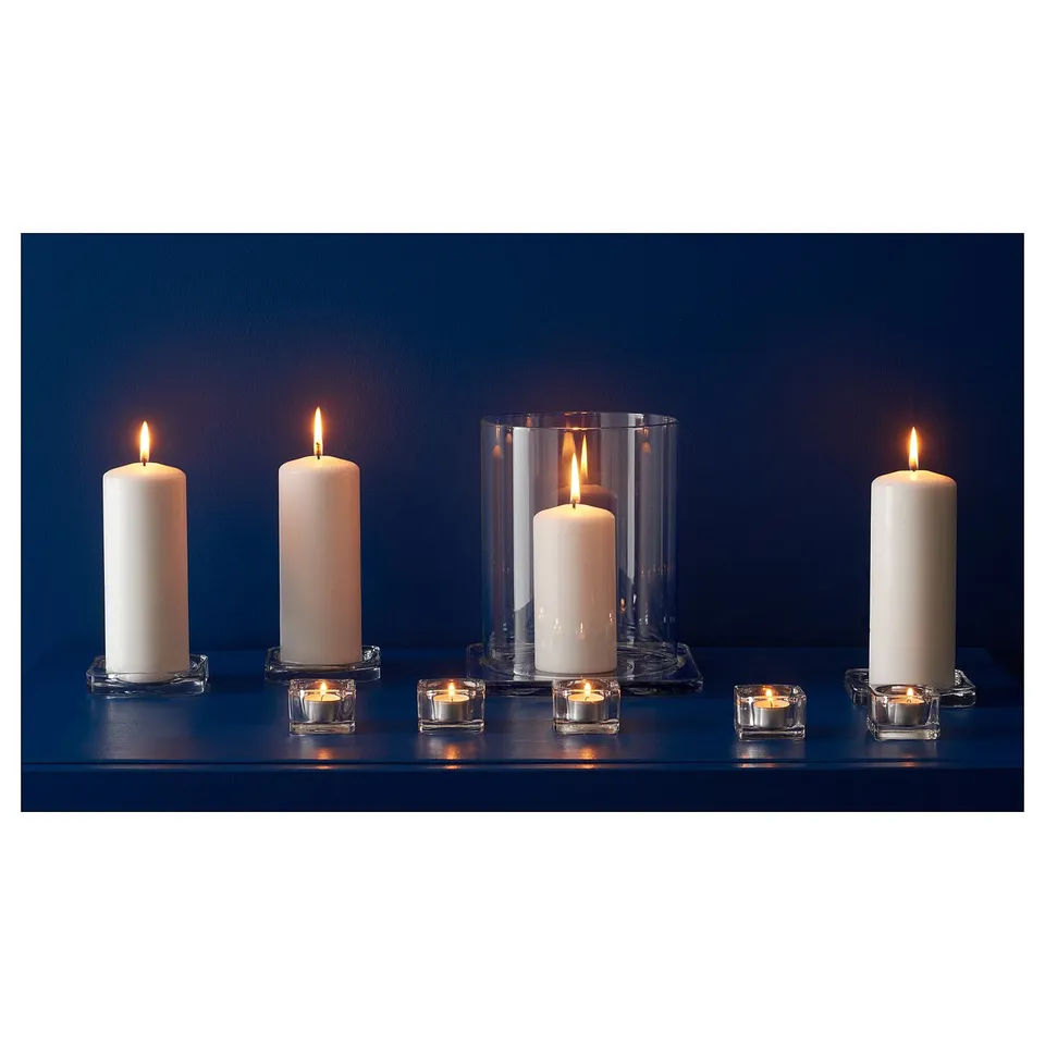 Six lit white candles in various clear glass holders, on dark blue surface.