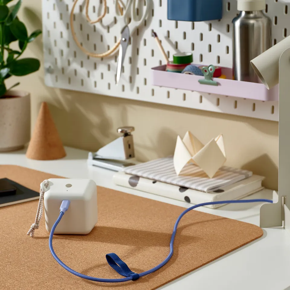 Organised desk with LILLHULT usb-c cable, blue, coiled on mat with origami paper and binder clips.