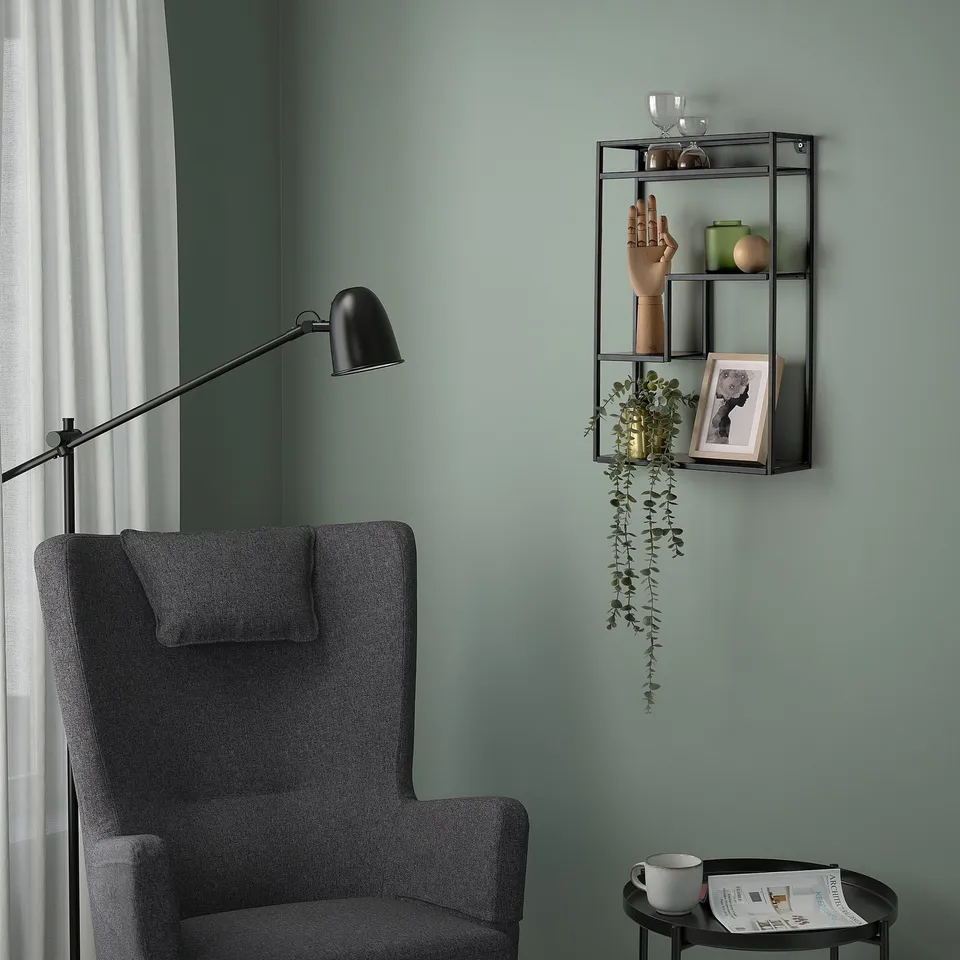 Grey LINDÅSEN wall shelf with items above armchair.