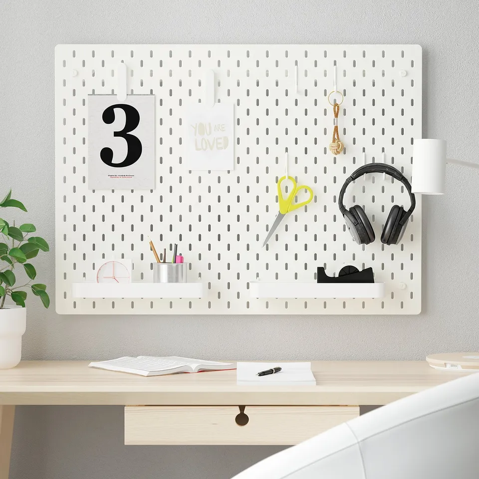 SKÅDIS pegboard organiser with desk items, including 3 frame, card, scissors, headphones, keychain, clock, pens, cup, and plant.