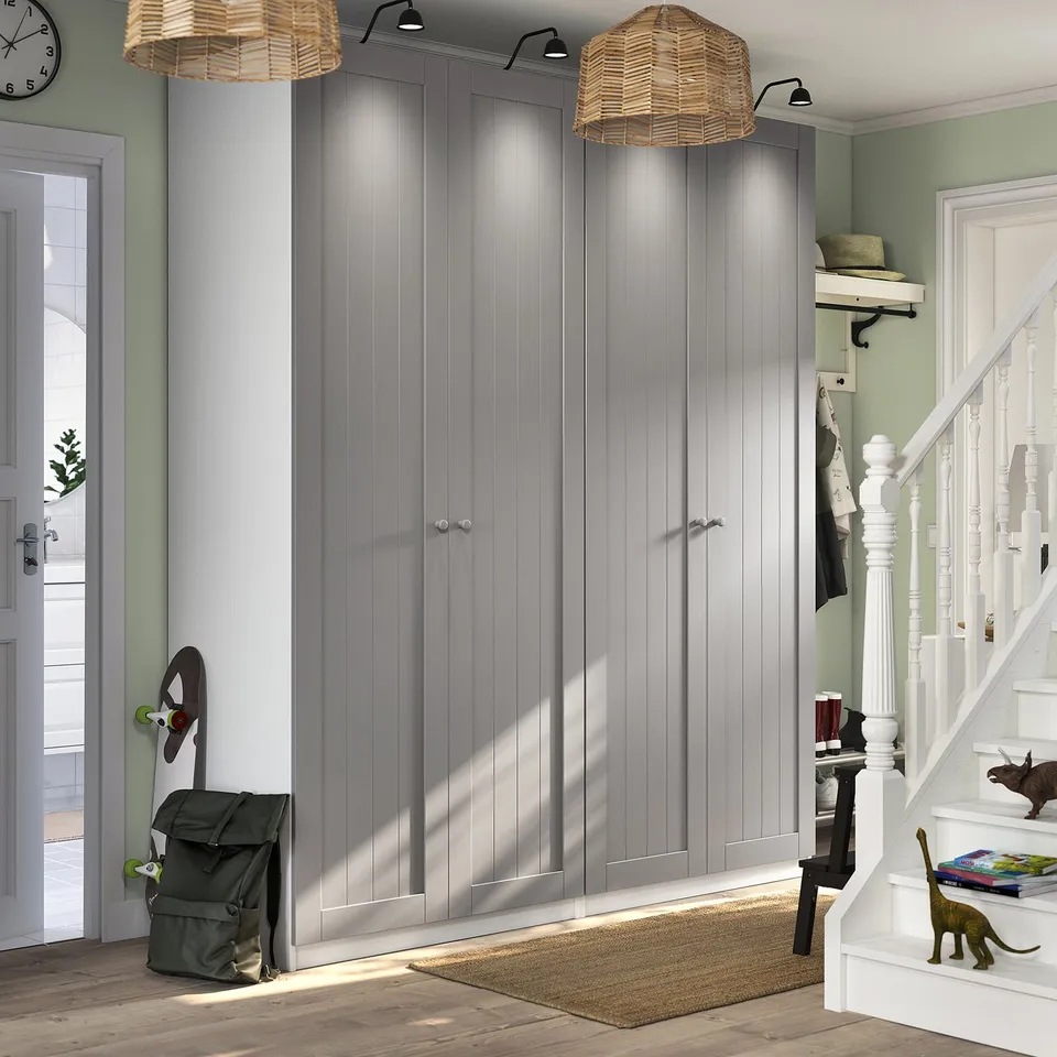 Spacious entryway with grey GULLABERG doors, white staircase, green backpack, warm wicker lamps.