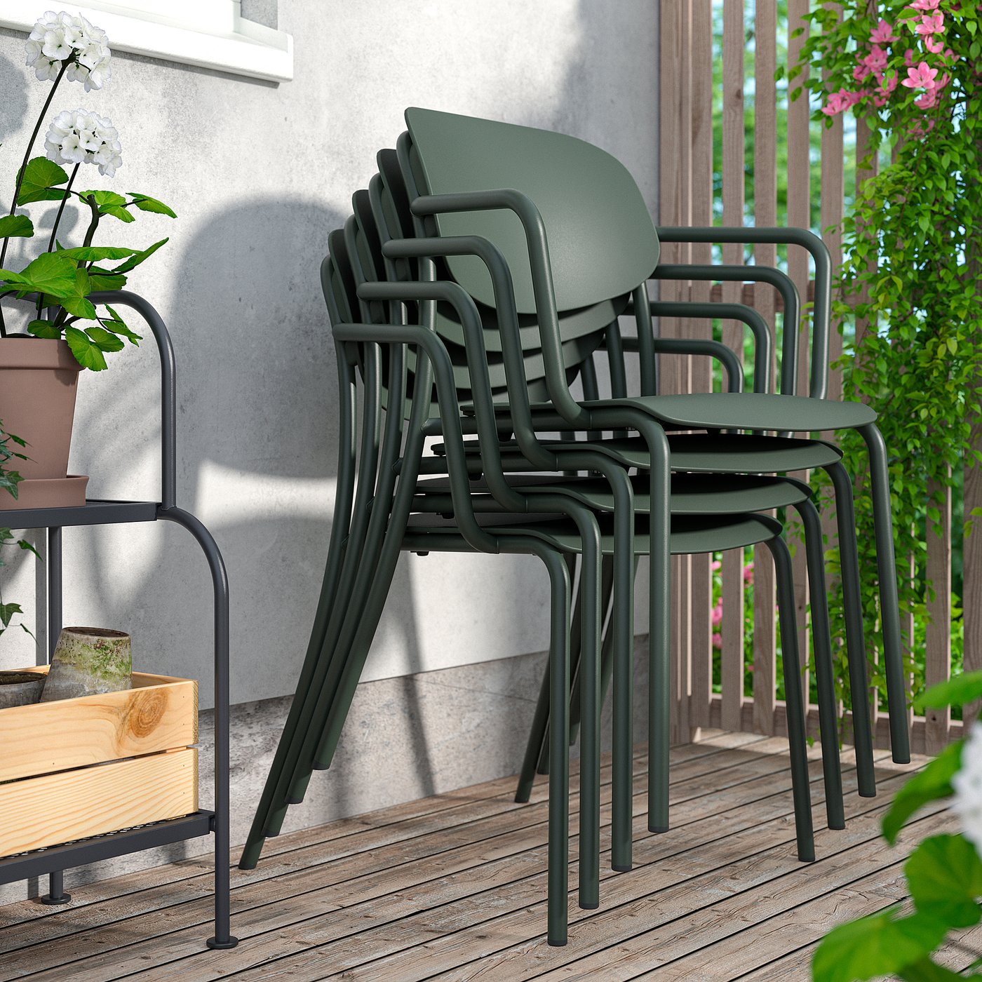 Stacked VISINGSÖ outdoor chairs, dark green, on wood deck by wall.
