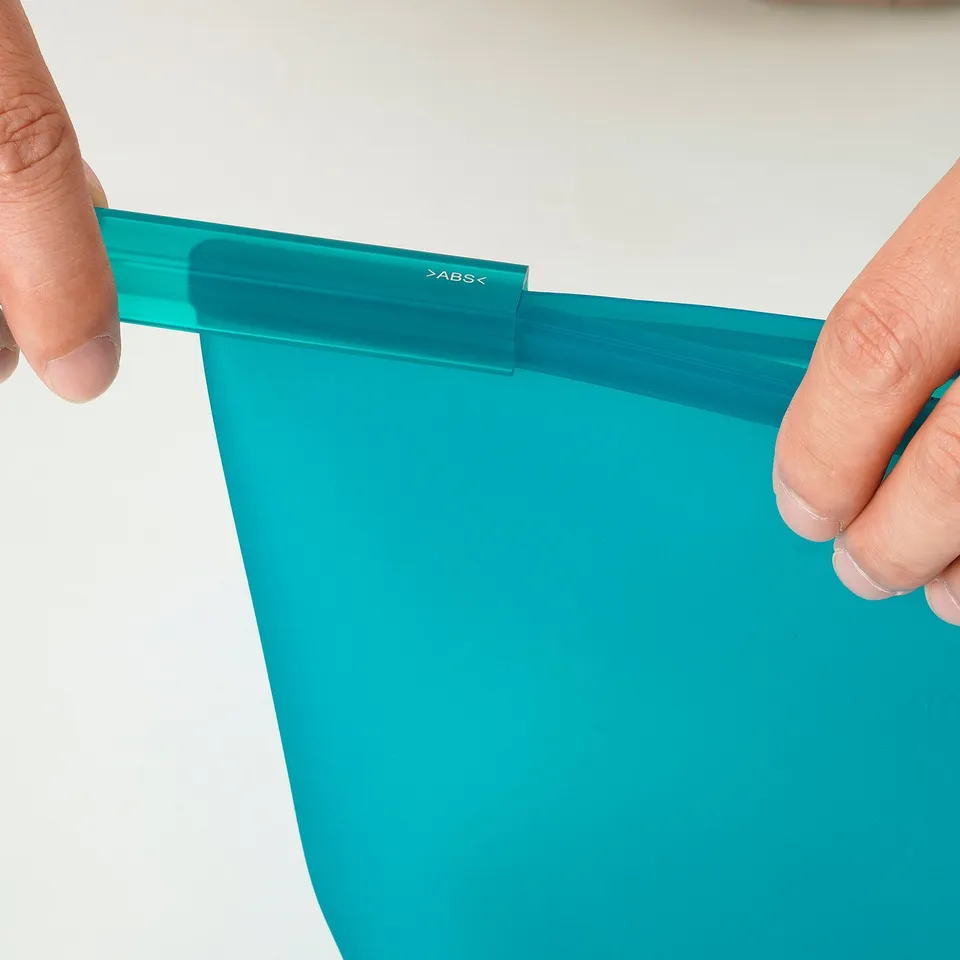 Hand holding a blue FILFISK bag, showing its resealable clip.