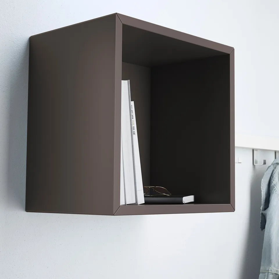 Dark cube shelf on wall holding books and glasses. Part of EKET storage system.