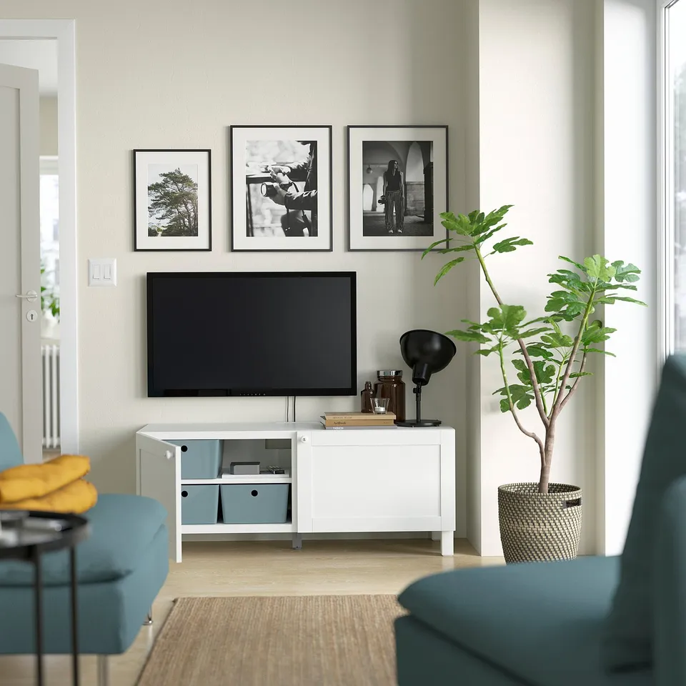 Modern living room with BESTÅ tv bench, black tv, and potted plant.