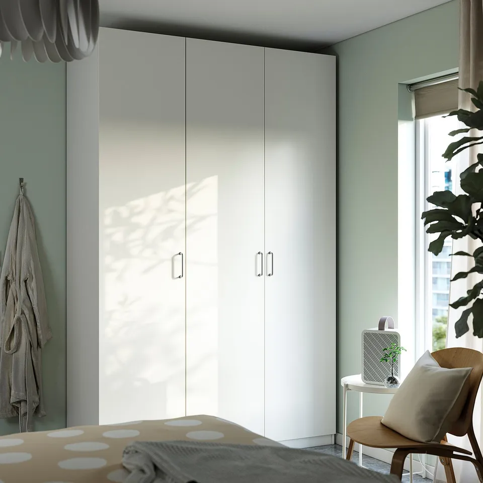 Modern bedroom with PAX wardrobe, chair, and window.