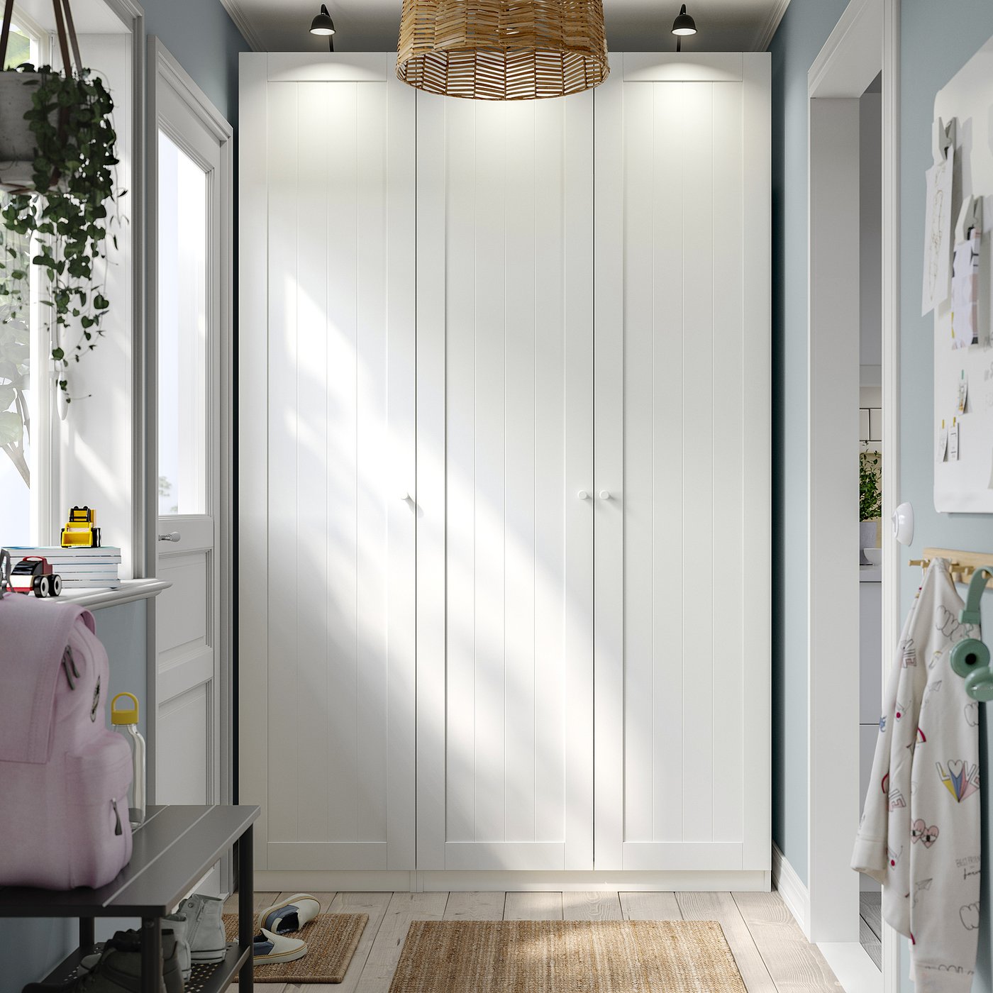 White PAX wardrobe with backpacks, toys, and bins, highlighted by pendant light.