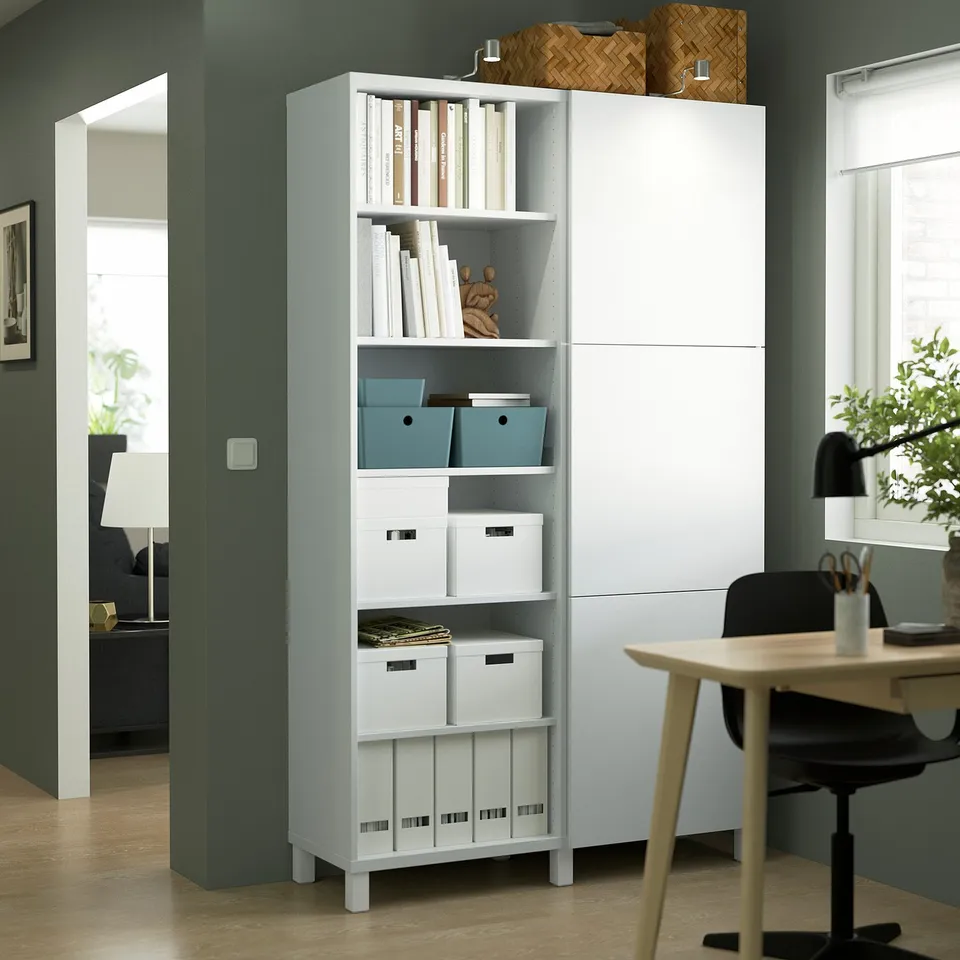 White BESTÅ storage unit with mixed open and closed shelves. Tall, adjacent living room scene, matching furniture.