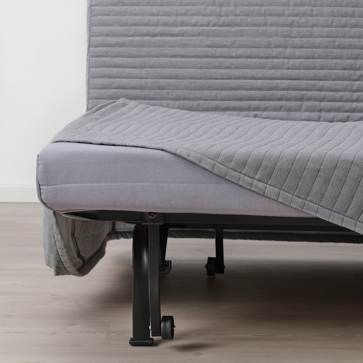 Convertible sofa-bed with steady mattress, showing frame and wheels for easy movement.