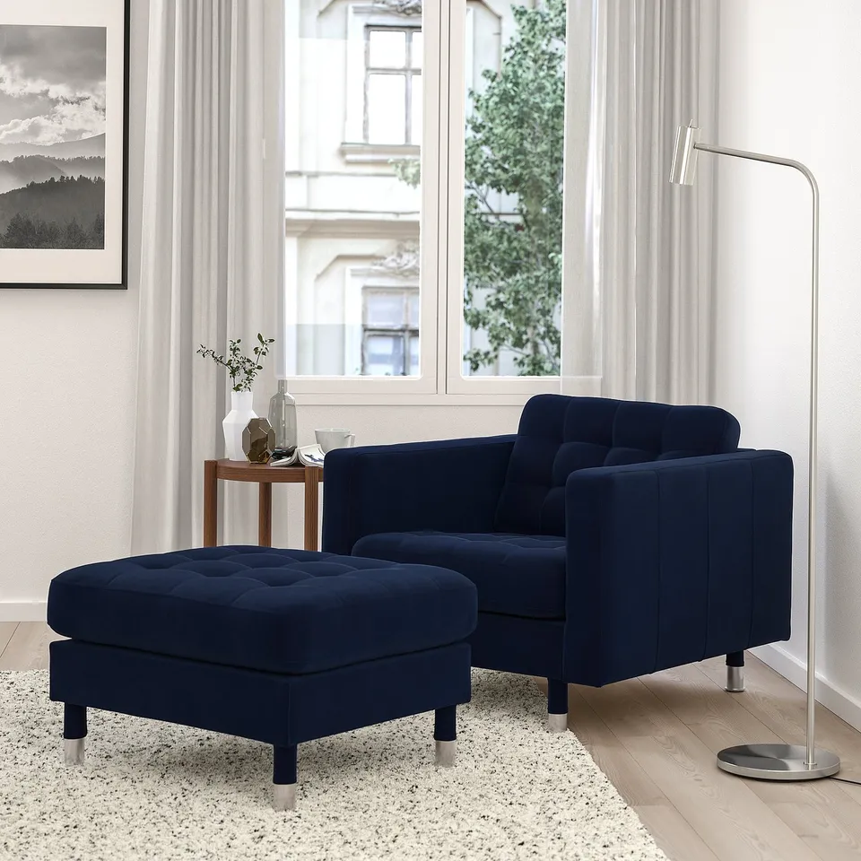 Modern living room with blue velvet chair, lamp, and city view.