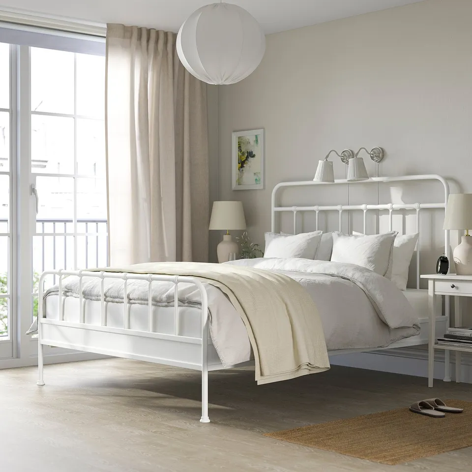 White STJÄRNÖ steel bed with curved head/foot, large window, white linens.