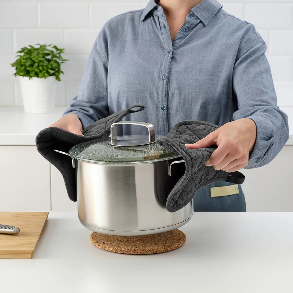Person holding lid with towel to avoid burns.