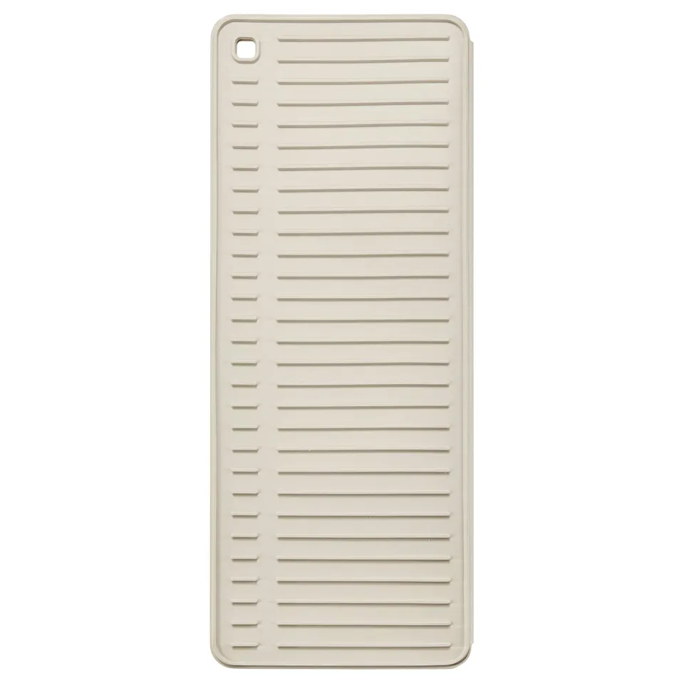 A RINNIG drying mat. Its white, rectangular, made of thermoplastic elastomer, with horizontal grooves for dishes.