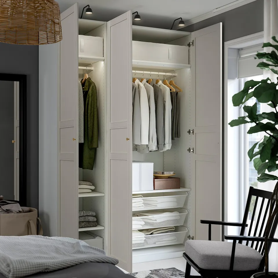 Well-organized closet with hanging clothes, shelves, and mesh drawers. Integrated lighting illuminates the space.