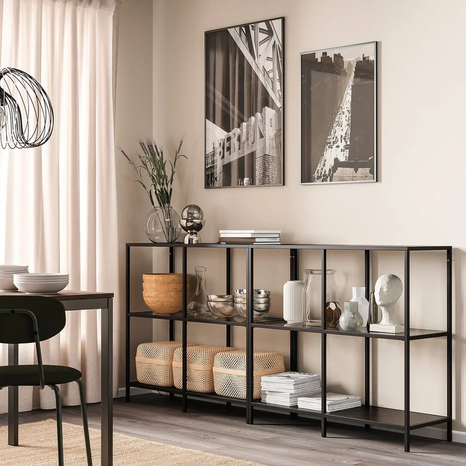 Minimalist room with VITTSJÖ shelf unit displaying decor, vases, bowls, books, and framed photos.