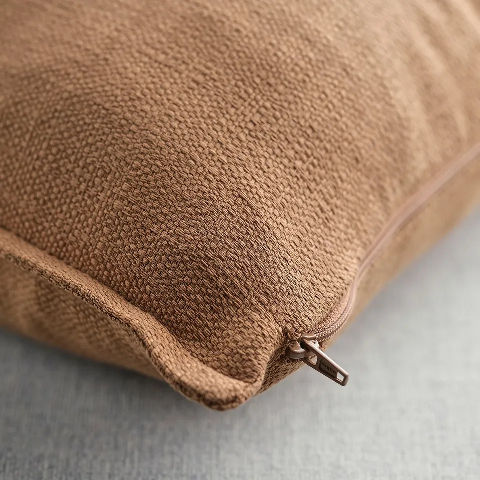 Close-up of recycled polyester cushion cover with zip, light brown, textured surface.