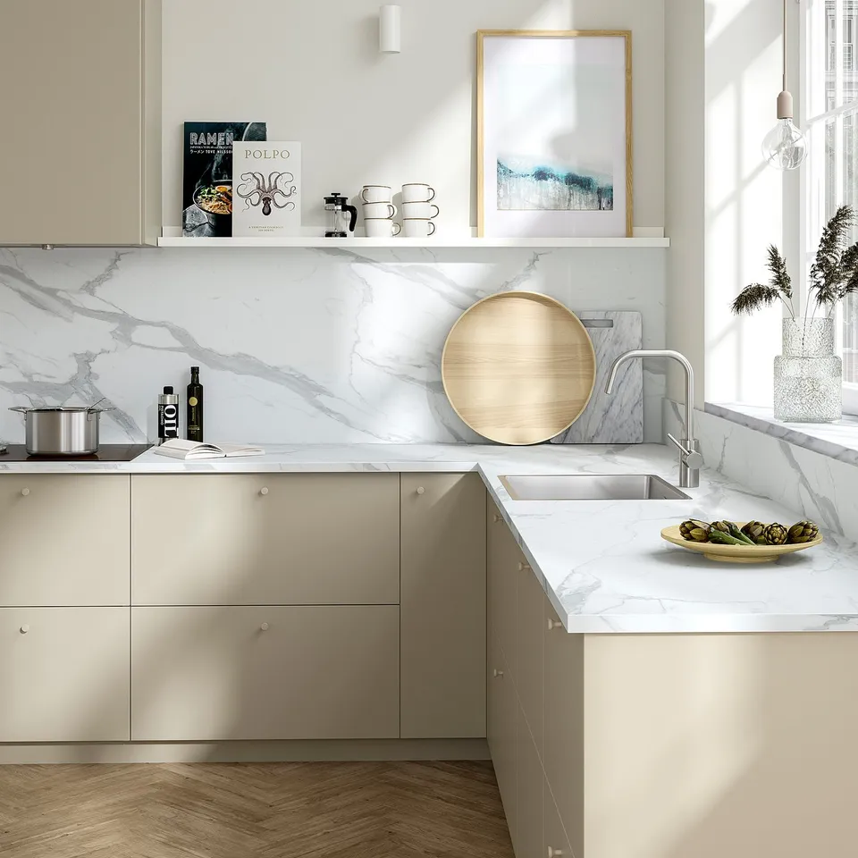 Modern kitchen with EKBACKEN marble-patterned countertop. A circular wooden tray and fresh produce, blending natural and elegant styles.