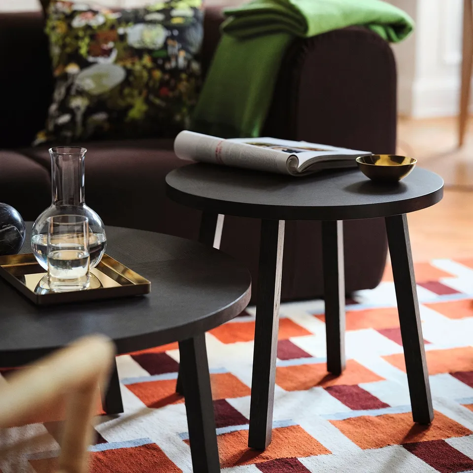 Modern living room with stockholm rug, round tables, and cosy couch with pillows.