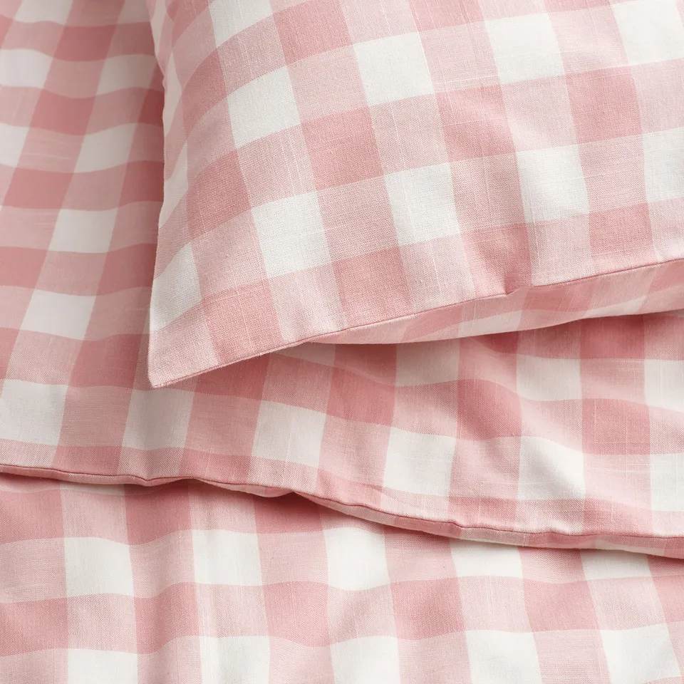 Light pink and white gingham duvet cover set in soft organic cotton, neatly folded to display quality texture and stitching.