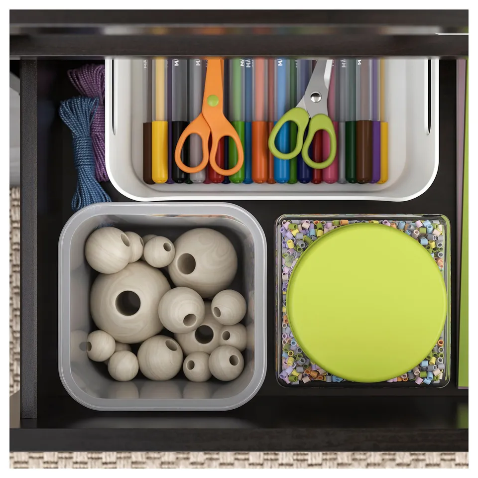 Organised drawer with coloured markers, scissors, wooden beads, and a lime green plate.
