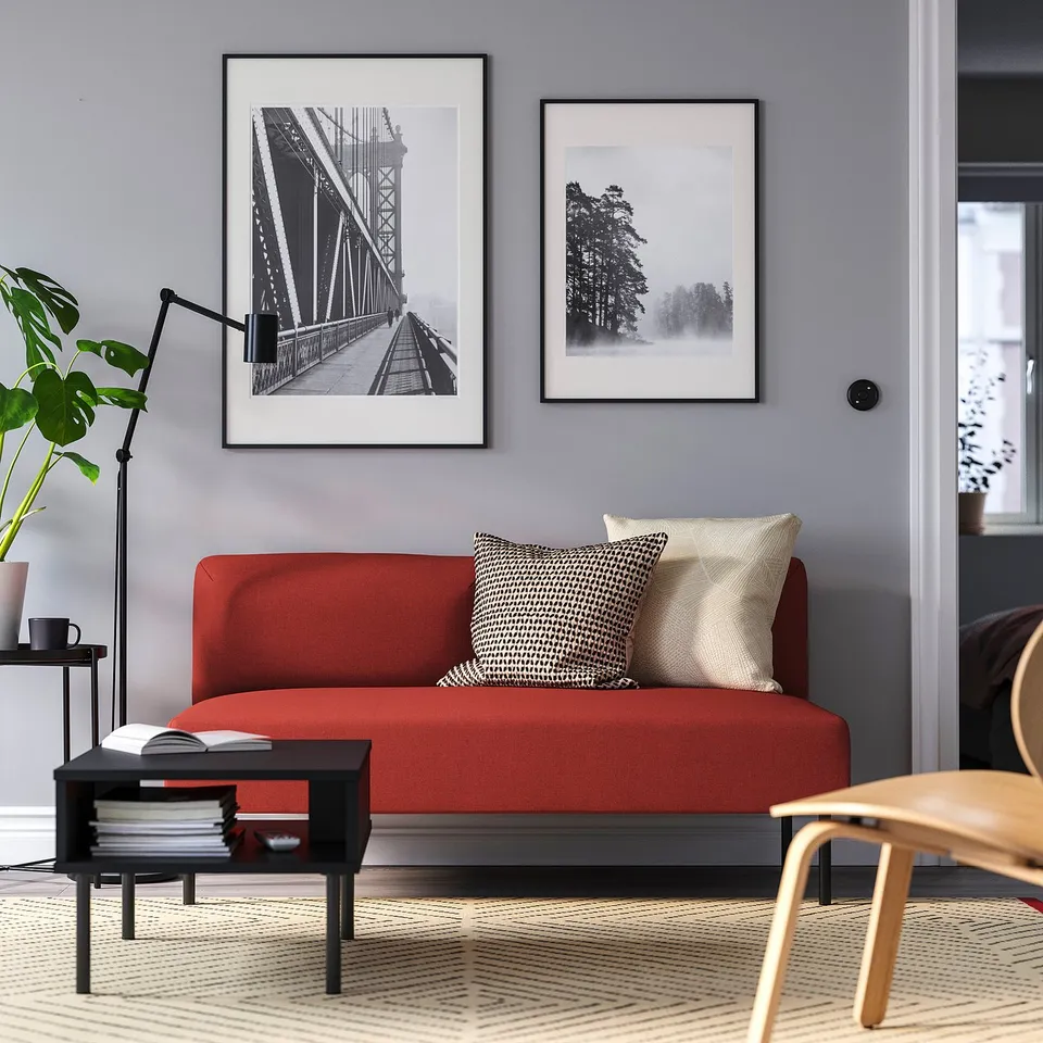 A small, modern living room with red LILLEHEM sofa, photos, coffee table, plant, and lamp.