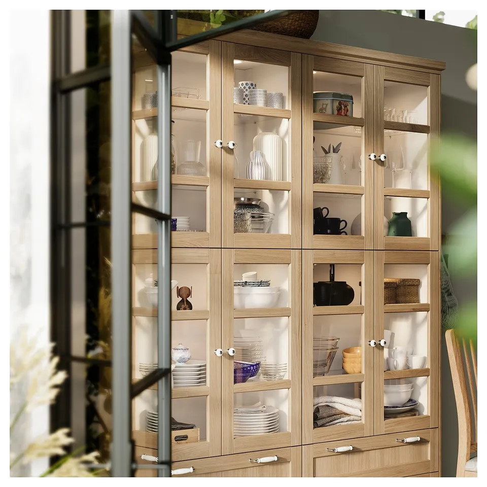 Wooden cabinet with glass doors, displaying white dishes and kitchenware.