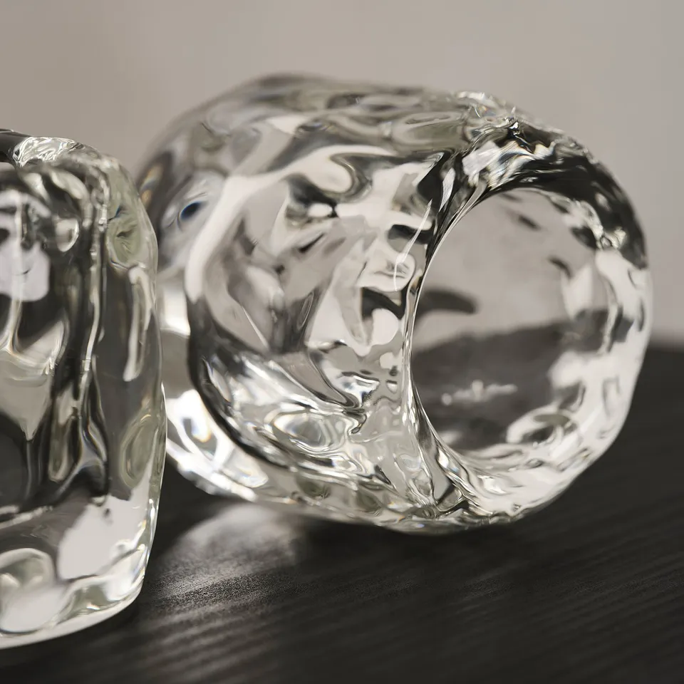 Tealight ice cube holder on dark wood, thick glass reflects light.