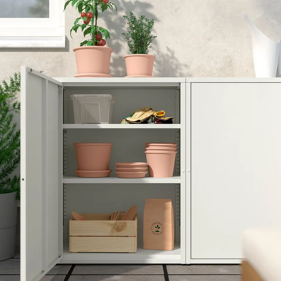 Open white SUNDSÖ cabinet displaying plant pots, gardening tools, and storage boxes; indoors.