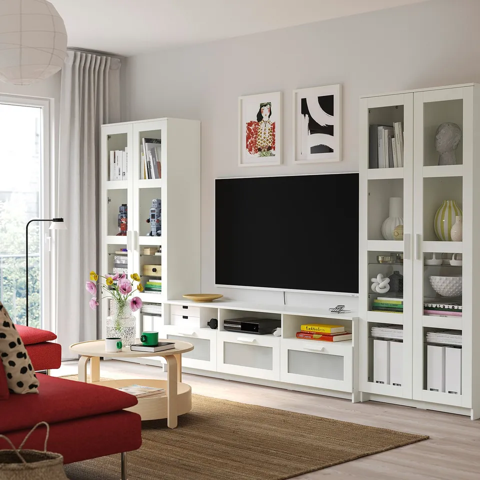 Modern living room with BRIMNES tv stand, mounted tv, colourful art, red sofa, and wooden coffee table.
