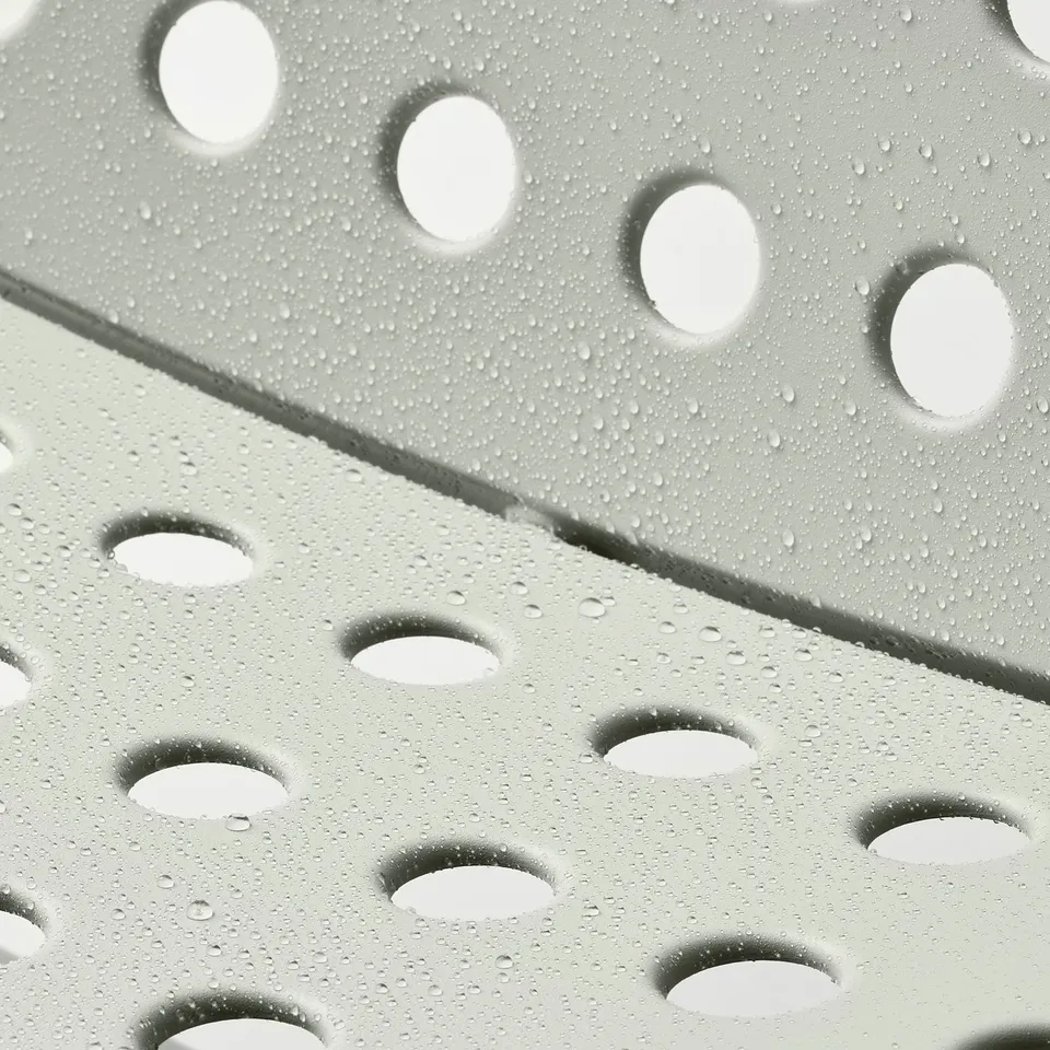 Close-up of SKOGSÖN chairs perforated metal seat, showing water droplets. Reflects comfort and durability for outdoor use.