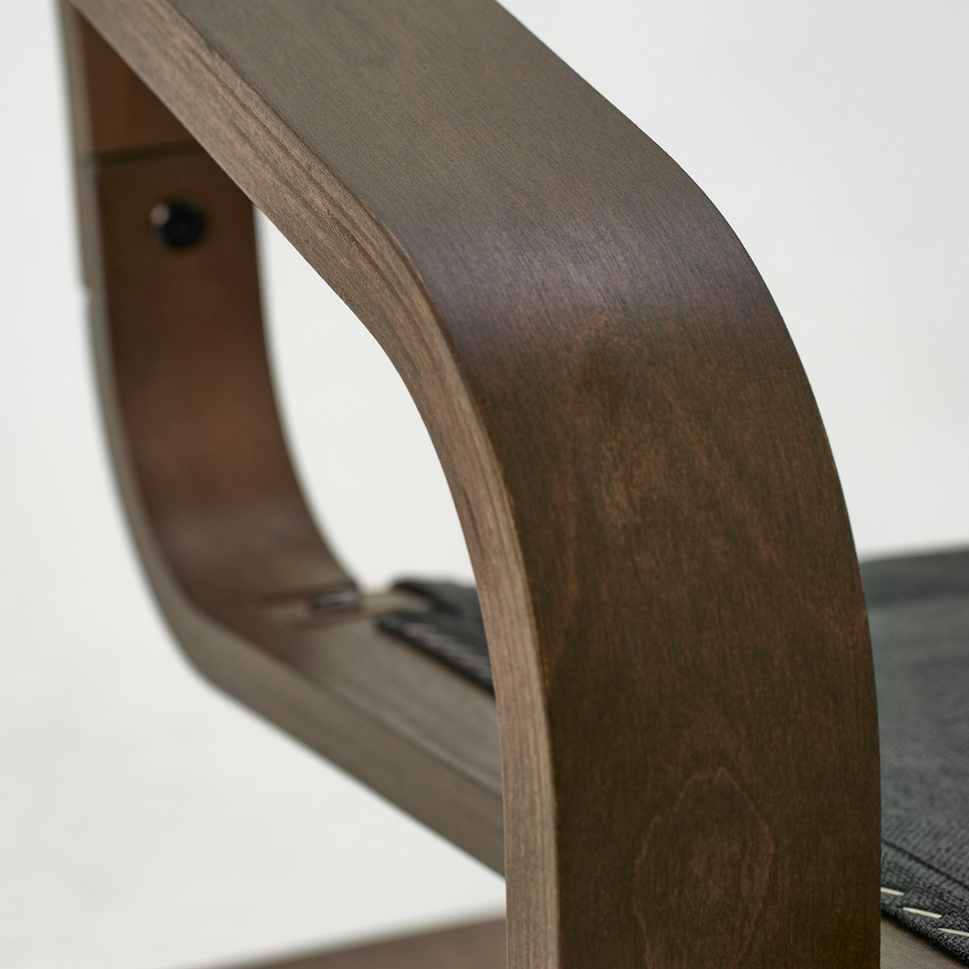 Dark wood curved armrest of a stylish, durable chair. Smooth, polished surface suggests high quality and comfort.