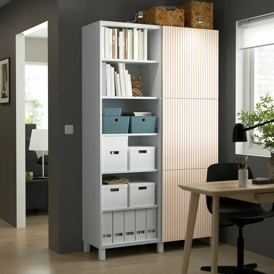 Modern BESTÅ grey storage unit with adjustable shelves, color-coded items, and birch veneer door in home office.
