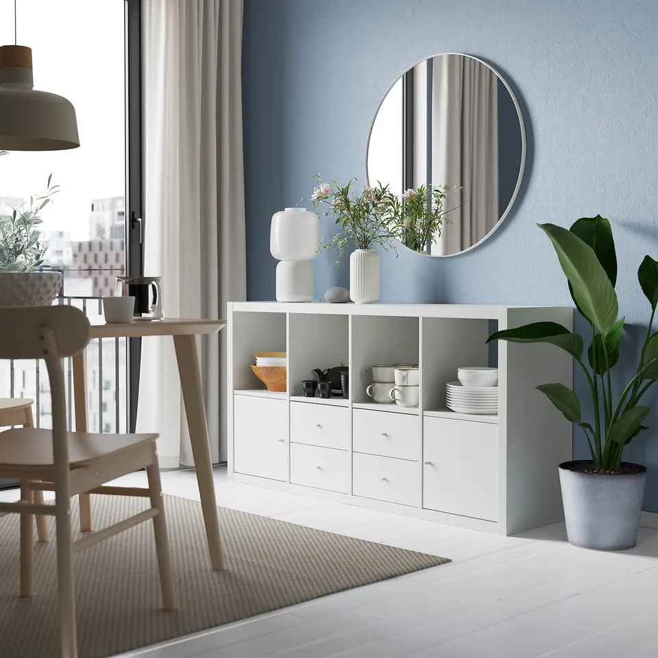 Living room with KALLAX unit against blue wall, mirror reflection, and dining table.