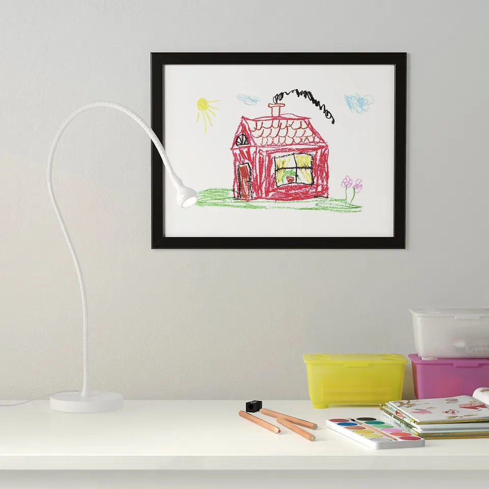 Framed kids drawing with house, lamp, & art supplies.