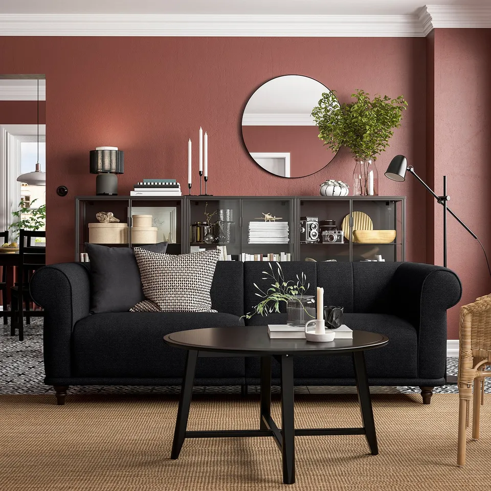 Black VISKAFORS sofa with round coffee table, red walls, and decorative shelves.