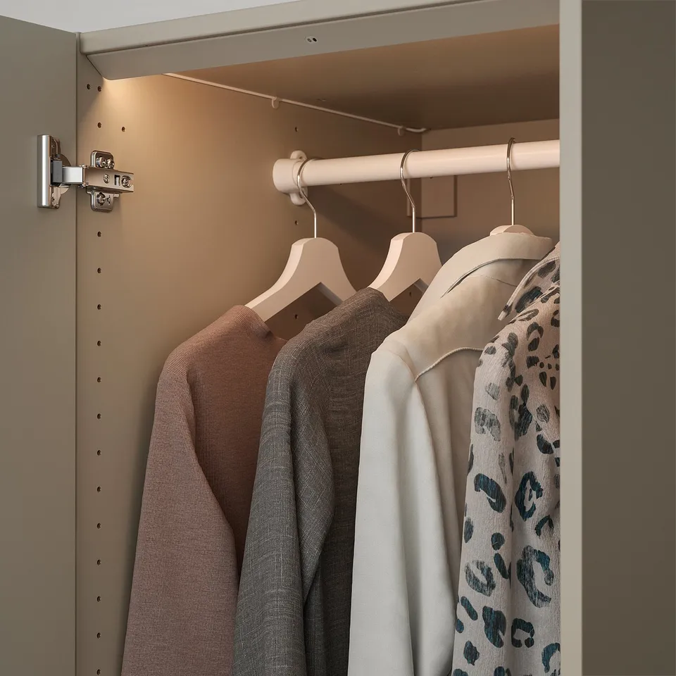 A modern wardrobe with led lights, illuminating clothes hangers inside. The lights automatically adjust when the door is opened or closed.