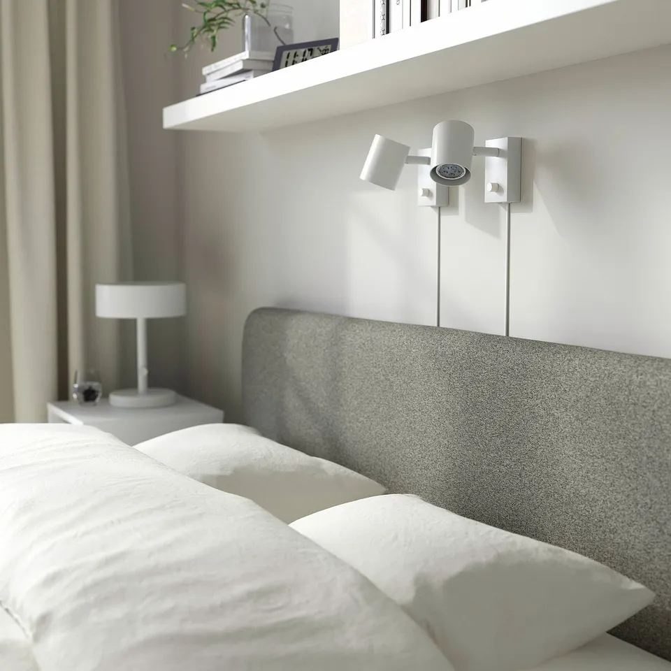 Modern bedroom with grey bed, white pillows, dual-light fixture, removable slipcover.