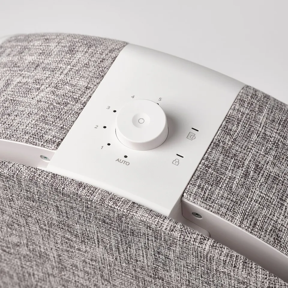 Modern air purifier with control dial; sleek, minimalist design; white finish; fabric-covered sides.